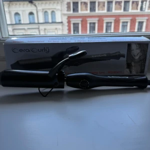 Svart locktång från GeraCurly 38mm - Säljer en svart locktång från GeraCurly med 38mm keramisk cylinder. Tången har justerbar temperatur mellan 120-200°C och en lång roterande sladd. Perfekt för att skapa stora, mjuka lockar. Snygg och stilren design.