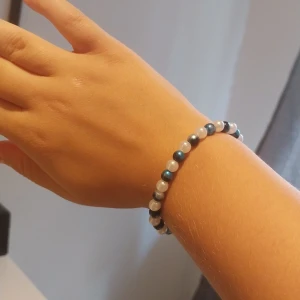 Pärlarmband i blått och vitt - Snyggt armband med pärlor i blått och vitt. Pärlorna är runda och sitter på en elastisk tråd, vilket gör det enkelt att ta på och av. Perfekt accessoar för att ge din outfit lite extra färg och stil.