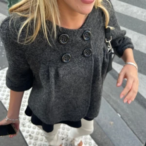 Trekvartsärmad kappa i ull - Säljer en mörkgrå kappa i ull. Köpt i Paris dyrt, finns inget märke på