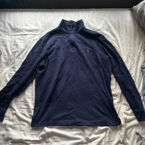 Marinblå half zip från Polo Ralph Lauren - Snygg marinblå långärmad tröja från Polo Ralph Lauren med klassisk half zip och broderad logga på bröstet. Tillverkad i mjuk bomull. Hög krage och stilren. Sitter som storlek M