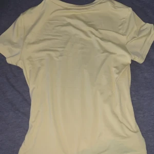 Ljusgul tight T-shirt - En enkel och fräsch ljusgul t-shirt med korta ärmar och rund hals. Perfekt för dig som gillar en clean och stilren look. T-shirten har en normal passform och är gjord i mjukt bomullsmaterial.