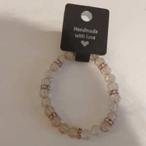 Handgjort pärlarmband med stjärnor - Superfint armband med genomskinliga pärlor dekorerade med små guldstjärnor och glittriga guldfärgade mellanringar. Perfekt accessoar för att lyfta din stil med lite extra shine.