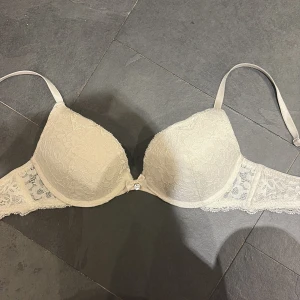Vit spetsig bh med rosett från hunkemöller  - Använd fåtal gånger så fortfarande i väldigt bra skick. Inköpspris 500kr. Liten slitning på insidan men inget som påverkar kvaliten eller utseendet på bh:N. Pris kan diskuteras 