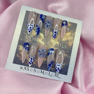 BleuFleur(XS);Long Stiletto - Snygga långa gelé press-on naglar i stilettoform med nude bas, blå och vita detaljer, prickar och blommor samt silverfärgade dekorationer. Kommer i XS: 14 mm, 11 mm, 11,5 mm, 10 mm, 8 mm. Perfekt för dig som vill ha en unik och kreativ nageldesign.