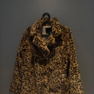 Leopardmönstrad pälsjacka från 157 - Säljer en fluffig och trendig pälsjacka från 157 i storlek S. Jackan har ett snyggt leopardmönster i bruna och svarta toner, bred krage och är helfodrad. Perfekt statement-plagg för dig som vill sticka ut och hålla dig varm.