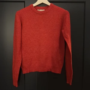 Röd stickad tröja från Pull&Bear - En enkel och snygg röd stickad tröja från Pull&Bear. Tröjan har rund halsringning, långa ärmar och ribbade muddar vid ärmslut och nederkant. Perfekt för lager-på-lager och passar till jeans eller kjol.
