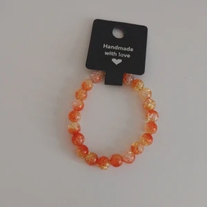 Handgjort orange pärlarmband - Superfint armband med glittriga pärlor i orange och ljusgula toner. Pärlorna är runda och sitter på en elastisk tråd, vilket gör det enkelt att ta på och av. Perfekt accessoar för att addera lite färg till din look.