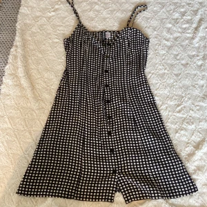 Svartvit rutig klänning - Superfin svartvit rutig klänning från Divided by H&M med knappar hela vägen framtill och smala axelband. Lätt och luftig modell som är perfekt för varma dagar. Snyggt A-linjeformad passform och klassiskt rutmönster💗