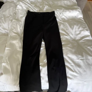 Svarta bootcut kostymbyxor Vero Moda - Snygga svarta kostymbyxor från Vero Moda i bootcut-modell. Byxorna har hällor för bälte och klassisk passform med lätt utsvängda ben. Perfekta för en clean och stilren look.