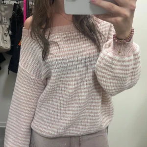 Randig offshoulder stickad tröja - Superfin stickad tröja i ljusrosa och vitt med randigt mönster.