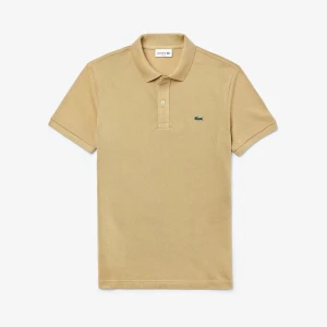 Beige pikétröja från Lacoste - Klassisk beige pikétröja från Lacoste med korta ärmar och krage. Tröjan har två knappar framtill och den ikoniska gröna krokodilloggan broderad på bröstet. Tillverkad i bomull för en skön och luftig känsla. Perfekt för en clean och stilren look.Om du behöver en annan storlek kan du kolla min profil.  