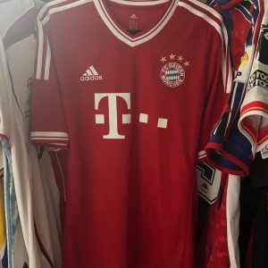 Bayern München 2013/14 äkta Götze 19 Adidas fotbollströja L - Röd Bayern München fotbollströja från Adidas med Götze 19-tryck på ryggen. Klassisk V-ringning, vita detaljer och klubbmärke på bröstet. Tillverkad i lätt och ventilerande climacool-material. Perfekt för dig som älskar Bundesliga och retrotröjor. Kvaliteten är perfekt förutom ryggen men det är lätt att fixa. 