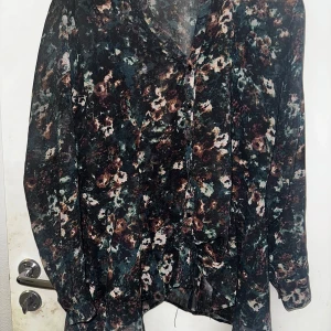 Rosebud flerfärgad blus - En vacker blus från Rosebud med ett unikt mönster i olika nyanser. Blusen har långa ärmar och en avslappnad passform, perfekt för både vardag och fest. Tunt material som passar till linnen.  100% polyester  Skickas 1-2 dagar efter genomförd betalning!