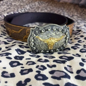 Country buckle belt - Snyggt brunt bälte i skinn med ingraverade blommor längs hela remmen. Skärpet är ifrån shein men är i väldigt bra kvalité!
