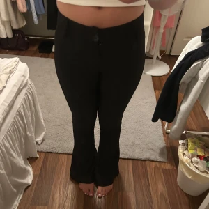 Svarta bootcut kostymbyxor - Säljer ett par svarta kostymbyxor med bootcut-snitt och mid-waist. Byxorna har lite speciella fickor på rumpan och två knappar vid gylfen☺️säljer då där är för små🥹
