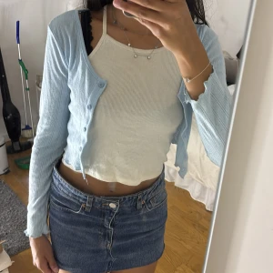 Ljusblå ribbad cardigan från SHEIN - Supersöt ljusblå cardigan från SHEIN i ribbat material med diskret mönster. Croppad modell med långa ärmar och knappar framtill. Perfekt att slänga över ett linne eller klänning för en chill look.