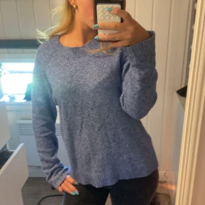 Blå stickad tröja med rund hals - Mysig blå stickad tröja med rund hals och långa ärmar. Tröjan har en relaxed fit och ribbade muddar vid ärmslut och nederkant. Perfekt för kyliga dagar och enkel att matcha med jeans eller kjol.