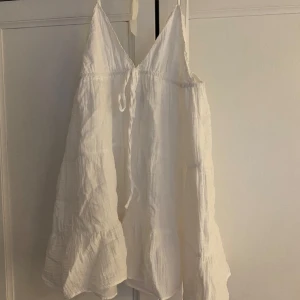 Vit sommarklänning från Zara - Luftig vit klänning från Zara med smala axelband och v-ringning. Klänningen är knappt använd utan bara använd 2 gånger. Tillverkad i ett mjukt, lätt tyg som känns skönt mot huden. 