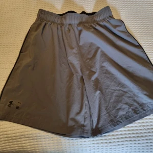 Grå shorts från Under Armour - Grå shorts från Under Armour med elastisk midja och logga på benet. Lätta och luftiga med fickor. Se gärna mina andra annonser och skapa bundles.