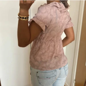 Rosa blommig blus med volang - Supersöt ljusrosa blus med blommigt mönster och volangdetaljer. Inte mina bilder, köpt på plick och inga defekter. Säljer pg av att jag behöver pengar❤️