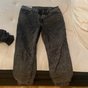 Svarta acid wash tapered jeans H&M - Säljer ett par svarta acid wash jeans från H&M i modellen Regular Tapered. Jeansen har klassisk femficksdesign, avsmalnande ben och cool tvättad look. Perfekta för dig som gillar en avslappnad men ändå trendig stil.