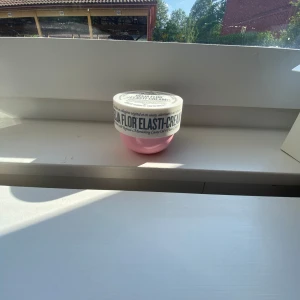 Sol de Janeiro Beija Flor Elasti-Cream - Beija Flor Elasti-Cream från Sol de Janeiro i en rund rosa burk med vit lock. Krämen är ljusrosa och har en mjuk, krämig konsistens. Perfekt för att ge huden extra fukt och glow. Burken är tillverkad av plast och har tydlig märkning på locket. Har använts lite. Pris går solklart att diskutera 💕🙌🏼