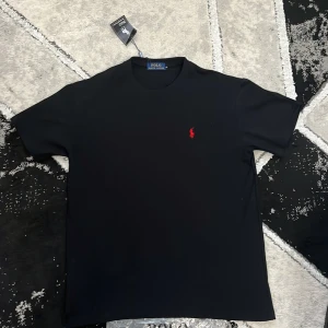 Svart t-shirt från Polo Ralph Lauren - Svart t-shirt från Polo Ralph Lauren, helt ny, skick 10/10, har aldrig använts, i storlek S Redo att skickas ut samma dag eller senast nästa vardag! Vid frågor eller funderingar är det bara att skriva!