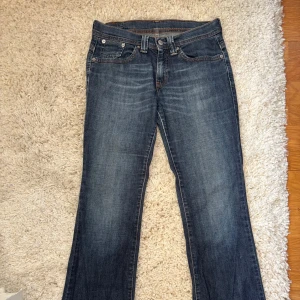 Levi's 517 blå bootcut jeans - Snygga blå Levi's 517 jeans med klassisk bootcut passform. Jeansen har en mörk tvätt med lätt slitning och kontrastsömmar. Femficksmodell i robust denim som ger en tidlös look. Perfekta för dig som gillar en avslappnad men ändå stilren vibe. Storlek 28x32💕 Midjemåttet är ca 37 cm💓 Pris kan diskuteras 💗