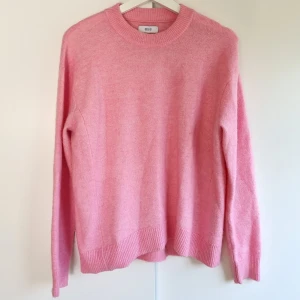 Rosa stickad tröja från Envii S/M - Supermysig rosa stickad tröja från Envii i storlek S/M. Tröjan har rund hals, ribbade muddar och är långärmad. Materialmixen består av akryl, polyester, ull och alpaka vilket gör den både mjuk och varm. Perfekt för dig som gillar färg och vill ha en chill vibe. Bra skick, lite nopprig men kan fixas lätt med en noppborttagare.