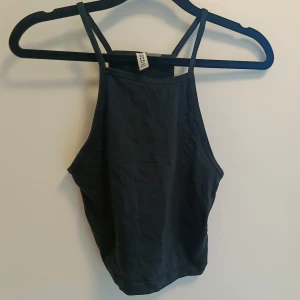 Svart linnetopp från H&M - En stilren svart linnetopp från H&M med smala axelband och hög halsringning. Toppen är ärmlös och har en enkel, clean look som passar perfekt till jeans eller kjol. Tillverkad i mjuk bomull för en bekväm känsla.