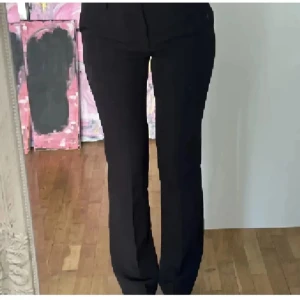 Svarta kostymbyxor med raka ben - Snygga svarta kostymbyxor med klassisk rak passform och hög midja. Byxorna har en stilren look och passar perfekt till en dressad outfit. Materialet känns mjukt och följsamt, vilket gör dem bekväma att bära hela dagen.