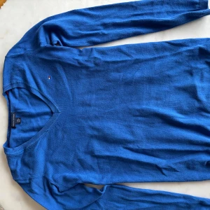 Blå v-ringad tröja Tommy Hilfiger - Snygg blå v-ringad tröja från Tommy Hilfiger. 
