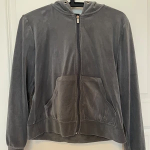 Grå velour hoodie från Gina Tricot - Mjuk och skön grå hoodie i velour från Gina Tricot. Tröjan har dragkedja framtill, huva och stora fickor. Perfekt för chill dagar eller när du vill ha en avslappnad look. Långärmad och loose fit för extra komfort.