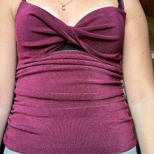 Vinröd omlott topp från Bik Bok XS - Snygg vinröd omlott topp från Bik Bok i storlek XS. Toppen har smala axelband, twistad omlott framtill och en liten cut-out under bysten. Materialet är mjukt och stretchigt, perfekt för att ge en slim passform. Passar dig som gillar detaljer och vill sticka ut.