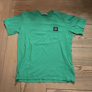 Grön  t-shirt - Snygg grön t-shirt från med klassisk logopatch på bröstet. T-shirten är i mjuk bomull och har en enkel, clean look med rund hals och korta ärmar. Perfekt för dig som gillar streetwear och vill sticka ut lite extra.