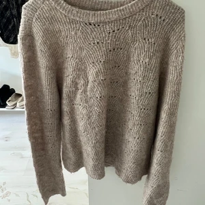 Beige stickad tröja från ONLY - Mysig beige stickad tröja från ONLY med långärmad design och snyggt mönsterstickat material. Tröjan har en rund halsringning och är perfekt för lager-på-lager under kyliga dagar. Passar dig som gillar en enkel men trendig look.