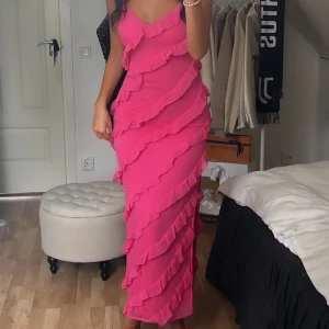 Rosa långklänning med volanger - Säljer en rosa långklänning med smala axelband och v-ringad front från Ginatricot, använd en gång. 