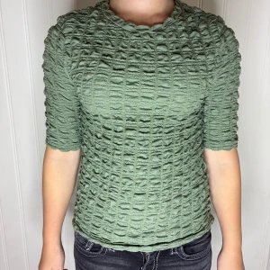 Grön ribbad topp från Lindex XS - Säljer en grön topp från Lindex i storlek XS. Toppen har ett unikt ribbat och strukturerat mönster, rund hals och halvlånga ärmar. Säljer på grund av att den är för liten. Pris kan diskuteras❤️