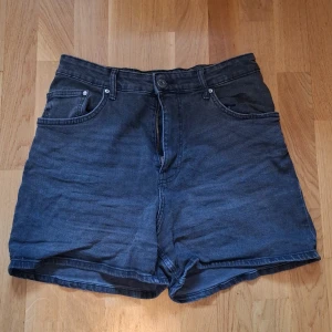 Svarta Shorts  - Svarta högmidjade shorts från H&M. De är väl använda och har lätta tecken på slitage. T.ex några trådar som lossade på lappen. (Jag har klipptbort dem.)