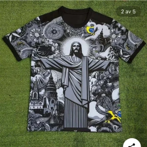 Brasil fotbollströja med Jesusstaty - Unik Brasil-fotbollströja från Nike med stort Kristusstaty-motiv och detaljerade svartvita illustrationer över hela framsidan. Gula Brasil-loggan och Nike-swoosh på bröstet. Kortärmad modell i lätt och ventilerande material, perfekt för match eller streetstyle.