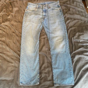 Levis 501 ljusblå jeans  - Ett par mångsidiga Levis 501or i en stilren ljus tvätt. Det klassiska, raka 501 snittet med knappgylf och mid rise. Använda men i gott skick. Storlek 33/32