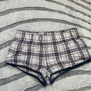pyjamas shorts - Supersöta rutiga shorts från Gina Tricot i storlek XS. De har en mjuk bomullskänsla och är vita med inslag av rosa och mörkblått. Modellen är low waist och har elastisk midja för extra komfort. Perfekta pyjamas shorts 