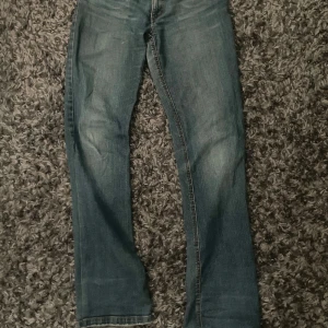 Blå bootcut jeans från Only - Snygga blå jeans från Only med klassisk bootcut-passform. Jeansen har fem fickor, orange kontrastsömmar och en liten röd Only Jeans-tag på bakfickan. Tillverkade i slitstarkt denimtyg som ger en cool och avslappnad look.