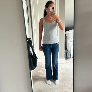 Mörkblå low waisted jeans - Säljer ett par mörkblå jeans med låg midja och fina detaljer! Som jag guld bruna sömmar och fem fickor med några knappar! Säljer pågrund av att dom är för små!💕