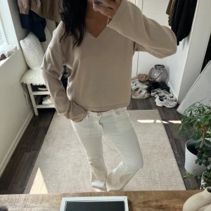 Beige v-ringad stickad tröja - En stilren beige stickad tröja med v-ringning och långa ärmar. Tröjan har en relaxed passform och är perfekt för lager-på-lager. Enkel att matcha med både jeans och kjol för en clean look. Kan även passa storlek S och M