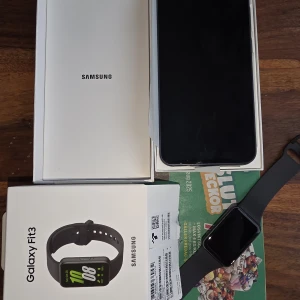 Samsung Galaxy Fit3 och samsung mobil - Säljer en Samsung Galaxy Fit3 aktivitetsklocka i svart med rektangulär display och silikonarmband. Perfekt för dig som vill hålla koll på träning, steg och hälsa. Stilren och modern design som passar till det mesta. Laddare och originalförpackning ingår. Samsung mobil i mycket gott skick