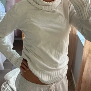 Vit polotröja med ribbade detaljer - Säljer en vit polotröja med bred ribbad krage, muddar och nederkant. Tröjan är långärmad och har en clean, enkel look som är lätt att matcha med olika outfits. Perfekt för dig som gillar stilrena och bekväma plagg.