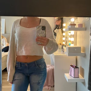 Ljusbeige croppad stickad tröja - Superfin ljusbeige croppad stickad tröja med lång ärm och bred, rundad halsringning. Tröjan har en loose passform och är perfekt att styla med jeans.