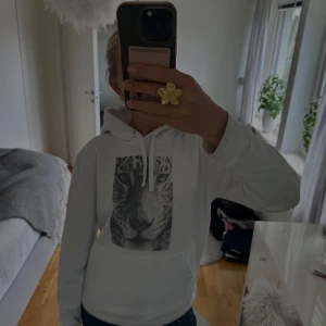 Hoodie med leopard-tryck från The Cool Elephant - Vit hoodie från The Cool Elephant i storlek XS. Framsidan har ett stort svartvitt tryck av ett leopardansikte. Skön och samtidigt väldigt cool!