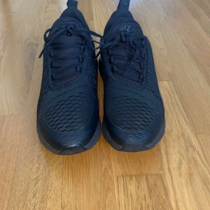 Svarta Nike Air Max 270 sneakers - Säljer ett par helsvarta Nike Air Max 270 sneakers med snygg mesh-ovandel och stor synlig Air-enhet i hälen. Skorna har snörning, rund tå och är tillverkade i syntet och textil. Perfekta för dig som gillar sportig och clean stil. Ord pris är 1400. Skorna har bara använts 2 gånger! Kontakta vid intresse!